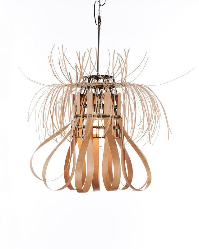 Single bulb suspended sculptural lighting with conical frame made from scrap metal opening downward, long strips of thick wooden reed looped down and thin reed flaring out from the top. Created by Lucy Slivinski 